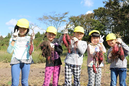 写真：サツマイモを掲げる子供たち
