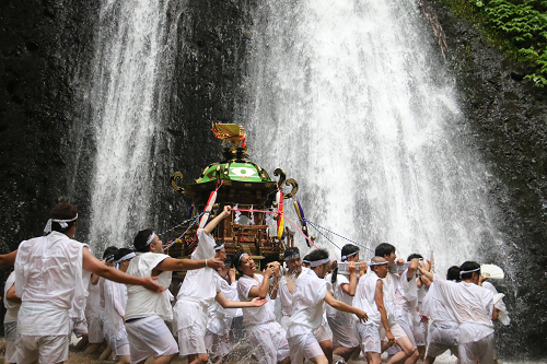 写真：滝下を神輿を担いで歩く男達