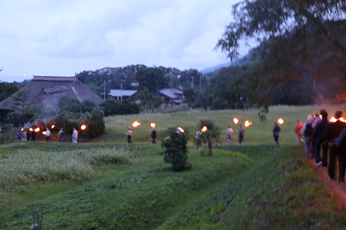 写真:たいまつを持って山道を降りる様子